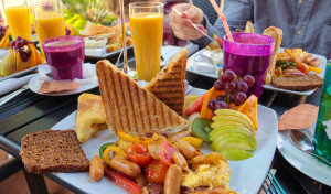 Brunch with susages, tomatoes, fruit, toast, coffee and orange juice